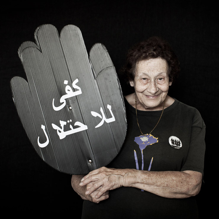 עליה שטראוס, 78, פעילה מזה 24 שנים בקבוצה התל-אביבית של נשים בשחור, אוחזת שלט עם הכיתוב "די לכיבוש" בערבית. (צילום: אקטיבסטילס)