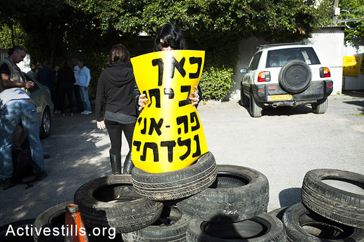 פעילה מול ביתה של רבקה חילובסקי, אוחזת שלט עליו כתוב "כאן ביתי – פה אני נולדתי". (צילום: שירז גרינבאום/אקטיבסטילס)