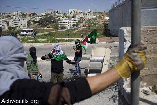 מפגינים פלסטיניים מיידים אבנים לעבר חיילים ישראלים בזמן הפגנה לשחרור האסירים הפלסטינים מול כלא עופר, הגדה המערבית, ה-4 לאפריל, 2014. (אקטיבסטילס)