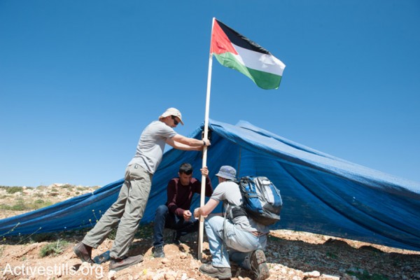 פעילים פלסטינים וישראלים מציבים דגל פלסטין סמוך לאוהל שהוקם ע"י מתנחלים על אדמה השייכת לכפר הפלסטיני חירבת א-נחלה, ה- 18 לאפריל, 2014. (אקטיבסטילס)