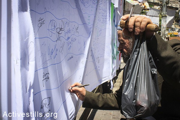 פלסטיני חותם על מכתב הזדהות אשר מיועד לעצירים מנהליים שובתי רעב בבתי כלא ישראליים, שכם, הגדה המערבית, ה-2 במאי, 2014. (אחמד אל-באז/אקטיבסטילס) 