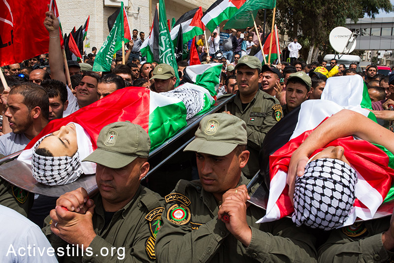 אנשי בטחון פלסטינים נושאים את גופותיהם של נאדים נווארה ומוחמד אבו-ט'אהר, שנהרגו בביתוניא, רמאללה, ה-16 למאי, 2014. (יותם רונן/אקטיבסטילס)