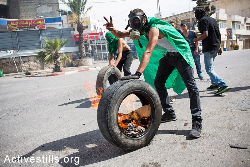 צעירים פלסטינים מתעמתים עם חיילים לאחר לוויות ההרוגים מאירועי יום הנכבה, ה-16 למאי, 2014. (יותם רונן/אקטיבסטילס)