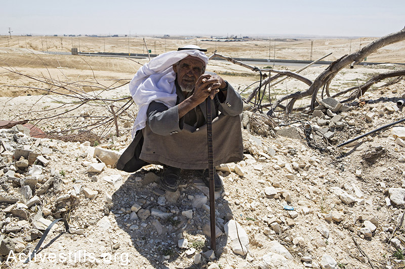 איש ממשפחת זאנון יושב על חורבות ביתו, דקות לאחר שרשות מקרקעי ישראל בגיבוי כוחות משטרה הרסו את הבית, ואדי אל-נעם, ה-18 במאי, 2014. (קרן מנור/אקטיבסטילס)