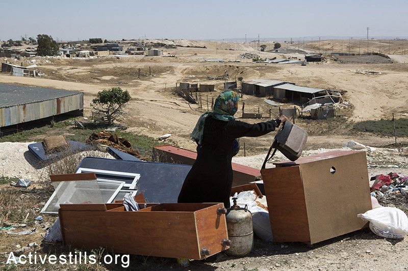 אישה ממשפחת זאנון מארגנת חפצים של המשפחה, דקות לאחר שרשות מקרקעי ישראל בגיבוי כוחות משטרה הרסו את ביתה, ואדי אל-נעם, ה-18 במאי, 2014. (קרן מנור/אקטיבסטילס)