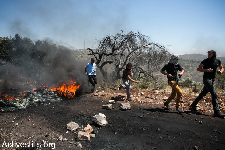 צעירים פלסטינים רצים ליד בריקדה במהלך הפגנה נגד הכיבוש בכפר קדום, ה- 2 למאי, 2014. (אקטיבסטילס)