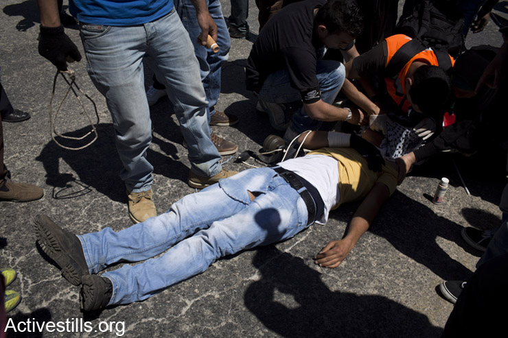 פצוע פלסטיני שרוע על הארץ לאחר שנורה ע"י חייל ישראלי במהלך הפגנה נגד הכיבוש, נבי סאלח, ה- 2 למאי, 2014. (אקטיבסטילס)
