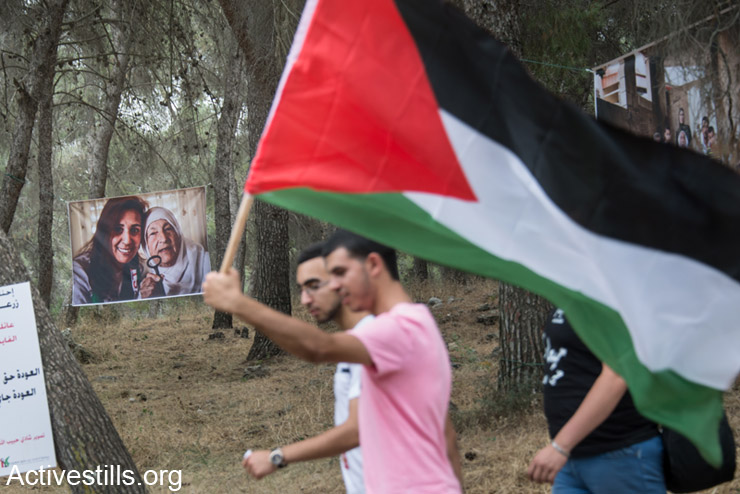 פלסטינים אזרחי ישראל צועדים ליד תמונות של פליטים פלסטינים במהלך תהלוכת השיבה לכפר לוביה, ה- 6 למאי, 2014. תהלוכת השיבה, המתקיימת באותו יום שבו נחגג בישראל יום העצמאות, מציינת את הנכבה הפלסטינית שבה נהרסו כ- 500 כפרים פלסטינים אשר תושביהם הפכו לפליטים. (אקטיבסטילס)