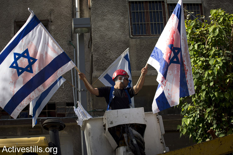 עובד של עיריית תל אביב מוריד דגלי ישראל, לאחר שלילה קודם נצבעו באדום, יפו, ה- 1 למאי, 2014. (אקטיבסטילס)