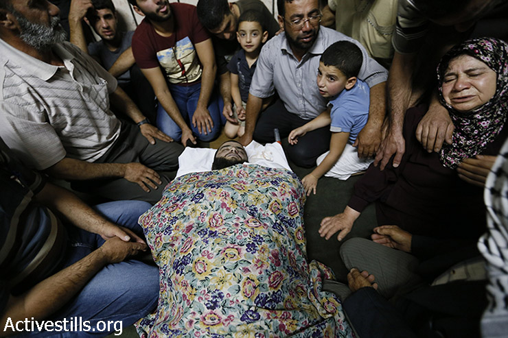 בני משפחה וחברים מתאבלים ליד גופתו של מוחמד חמאמרה בן ה-33. חמאמרה נורה בחזהו מאש חיה במהלך הפגנה נגד התקיפה הישראלית ברצועת עזה. הלוויתו נערכה בחוסאן, סמוך לבית לחם, 22 ביולי 2014. (מוסטפא באדר/ אקטיבסטילס)