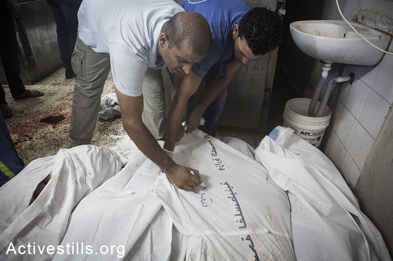 ממיינים גופות בבית החולים אל-שיפא, ה-20 ליולי, 2014. גופות הושארו שעות ארוכות על הרצפה בשל חוסר מקום. (אן פאק/אקטיבסטילס) 