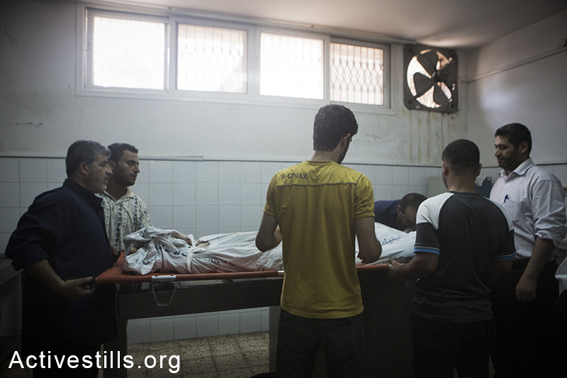 קרוב משפחה מנשק גופה בבית החולים אל-שיפא, עזה, ה-20 ליולי, 2014. (באסל יאזורי/אקטיבסטילס)