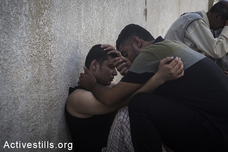 קרובי משפחה אבלים בבית החולים אל-שיפא, עזה, ה-20 ליולי, 2014. (באסל יאזורי/אקטיבסטילס)