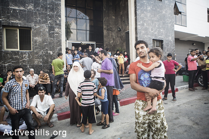 תושבים משכונת אל-סג׳עיה מבקשים מחסה מחוץ לבית החולים אל-שיפא, לאחר תקיפת הצבא באל-סג׳עיה שהרגה מעל 60 תושבי השכונה, ה-20 ליולי, 2014. (באסל יאזורי/אקטיבסטילס)