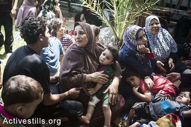 קרובי משפחה שנמלטו מאזור אל-סג׳עיה לאחר תקיפת הצבא שהרגה מעל 60 תושבי השכונה, יושבים ליד בית החולים אל-שיפא בחפשם מחסה, ה-20 ליולי, 2014. (באסל יאזורי/אקטיבסטילס)