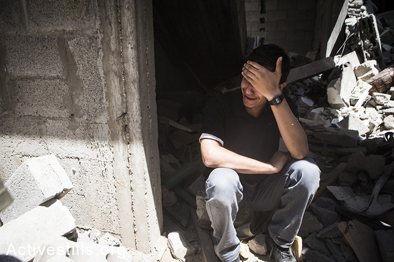 תושבי אל-סג׳עיה יושב על חורבות ביתו לאחר תקיפת הצבא שהרגה מעל 60 תושבי השכונה, ה-20 ליולי, 2014. (באסל יאזורי/אקטיבסטילס)