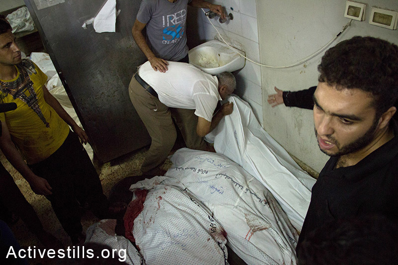 קרוב משפחה מנשק את גופות בני משפחתו בבית החולים אל-שיפא. עזה, ה-20 ליולי, 2014. (אל פאק/אקטיבסטילס)