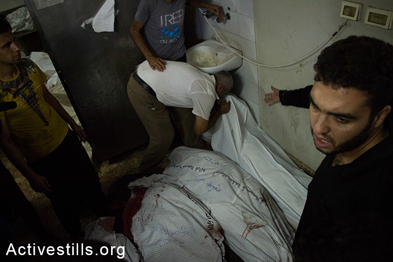 קרוב משפחה מנשק גופה בבית החולים אל-שיפא, עזה, ה-20 ליולי, 2014. (באסל יאזורי/אקטיבסטילס)