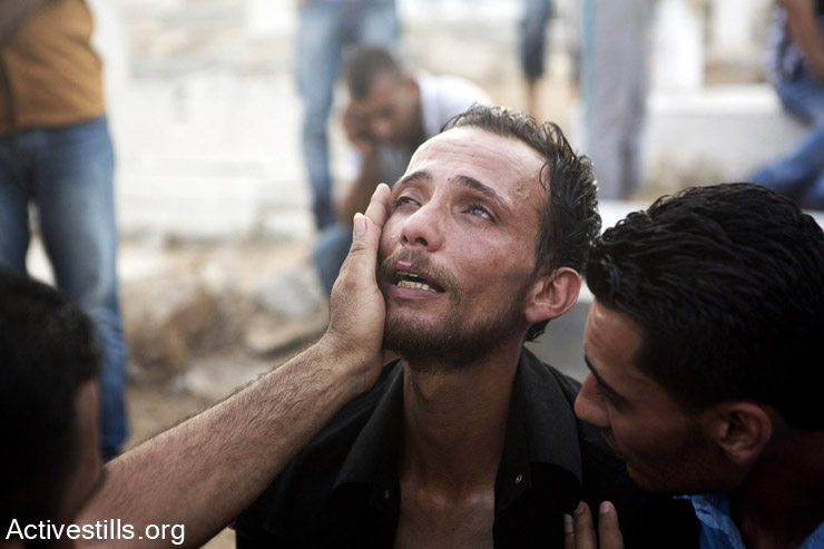 קרוב משפחה של אחד מהילדים שנהרגו במחנה הפליטים אל-שאטי מתאבל במהלך הלוויה, עזה, 28 ליולי, 2014. פיצוץ שארע במחנה הפליטים גרם למותם של עשרה, רובם ילדים, ולפציעתם של כארבעים אנשים. (אן פאק/אקטיבסטילס)