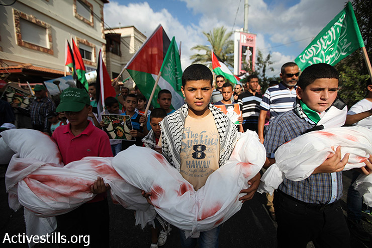 ילדים פלסטינים מחזיקים בבובות עטופות בבד לבן ומוכתמות בצבע אדום, במהלך הפגנה נגד התקיפה הישראלית בעזה, תמרה, ישראל,  2 באוגוסט 2014. (פיאז אבו רמלה / אקטיבסטילס)