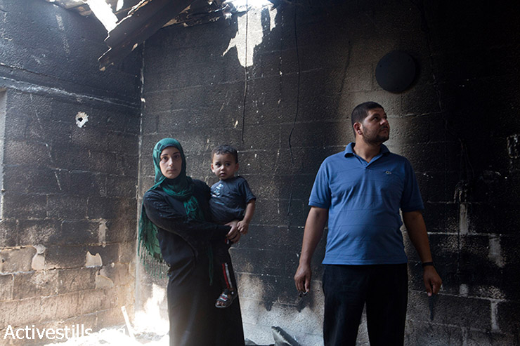 בני משפחת אל-קפרנה בדירתם שנהרסה על ידי התקפה ישראליות בבית חנון, צפון רצועת עזה, 4 באוגוסט, 2014. בני המשפחה חזרו להציל במהירות כמה מחפציהם במהלך הפסקת אש קצרה. (אן פאק / אקטיבסטליס)