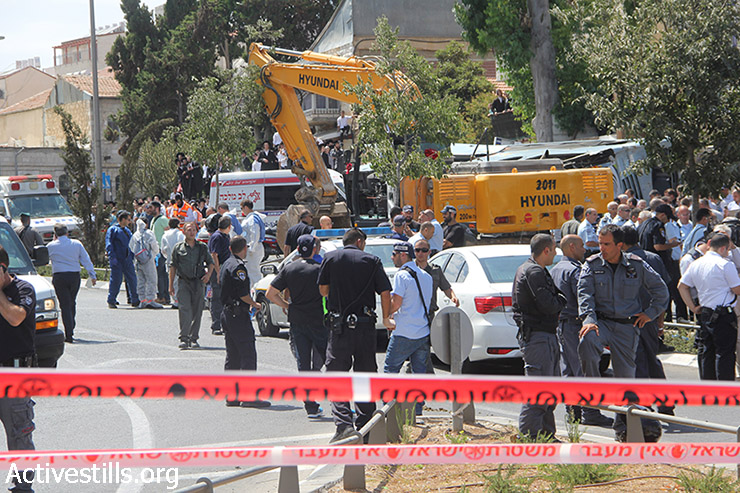 שוטרים וחובשים מתאספים בזירת פיגוע לאחר שגבר פלסטיני בטרקטור דרס אנשים והפך אוטובוס בירושלים, הרג אדם אחד ופצע כמה, 4 באוגוסט 2014. (פיאז אבו רמלה / אקטיבסטילס)