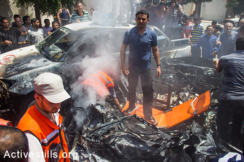 פלסטינים בודקים את הנזק לאחר הפצצת מכוניתו של שר המיסים של החמאס, העיר עזה, ה 24, לאוגוסט, 2014. (באסל יאזורי/אקטיבסטילס)