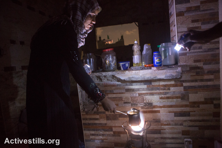 בני משפחת עאטש מחממים מים בחדר שנשאר על תילו בביתם ההרוס, שג׳יעה, ה-5 לספטמבר 2014. (אקטיבסטילס)