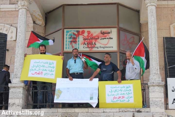 פעילים מניפים שלטים ממרפסת בניין החברה ברמאללה. (אחמד אל-באז/אקטיבסטילס)