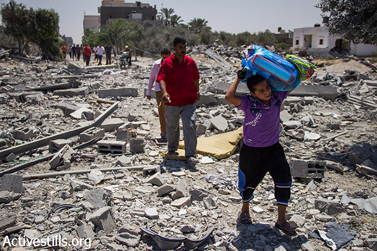 לד פלסטיני נושא חפצים אישיים שחולצו מהכפר ח'וזאעה, שעבר התקפות אינטנסיביות ונהרס במידה רבה במהלך המתקפה הישראלית. 1 באוגוסט, 2014.(אקטיבסטילס)