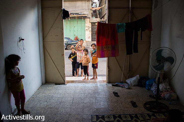 משפחת אל-זענין אשר ברחו מביתם בבית חאנון חיים בחנות ריקה ללא חלונות או שירותים סמוך לבית החולים כמאל עדוואן בג'באליה. 24 ביולי, 2014. (אקטיבסטילס)