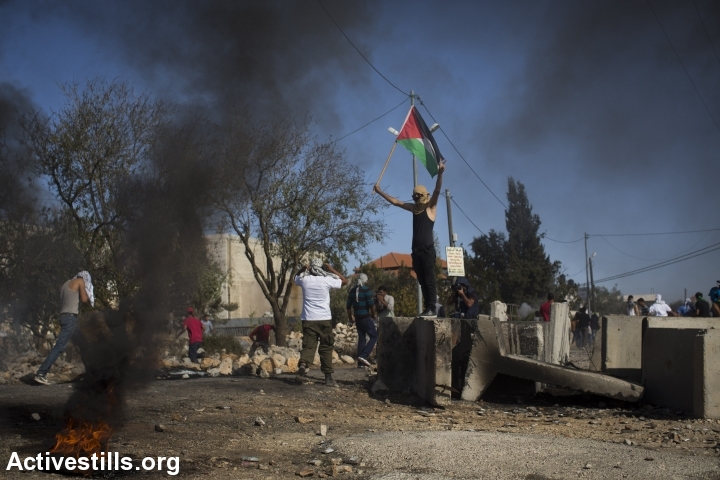 צעיר פלסטיני מניף דגל פלסטין במהלך עימותים לאחר הלוויתו של אורווה חאמד, סילוואד, הגדה מערבית, 26 אוקטובר, 2014. אורן זיו/אקטיבסטילס