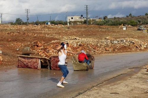 מפגין חבוש מסכת אוקופיי מיידה אבן לעבר המחסום בנבי סלאח. צילום: אבי בלכרמן