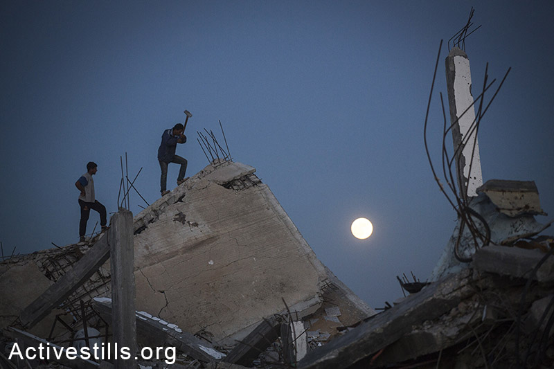 פלסטינים אוספים מתכות מבתיהם ההרוסים בכפר חוזעה שבמזרח רצועת עזה. 6 בנובמבר, 2014. (אן פק/אקטיבסטילס)