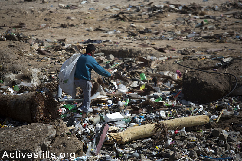 ילד מחפש בקבוקים למחזור כדי להרוויח מעט כסף, ליד חוף עזה, רצועת עזה, 12 פברואר, 2015. אן פאק / אקטיבסטילס