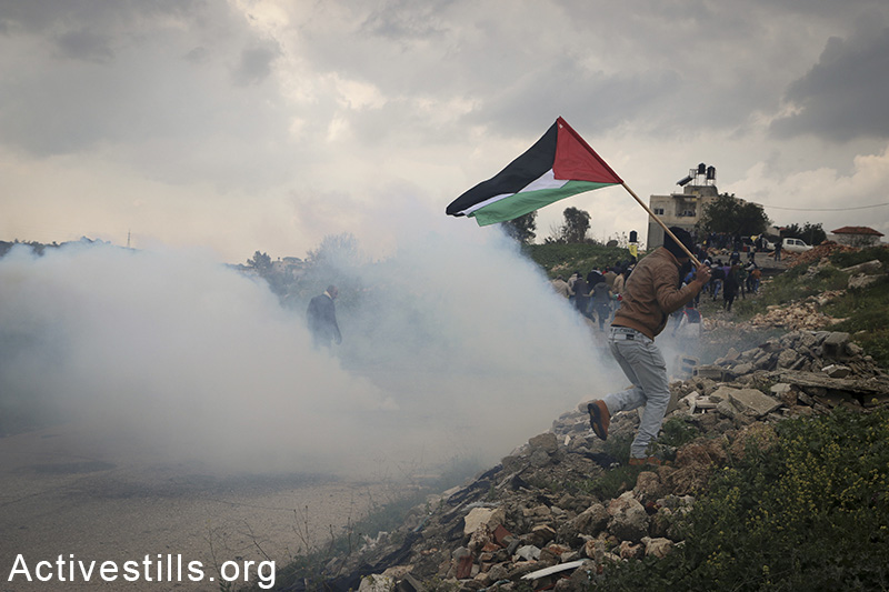 פלסטיני רץ מגז מדמיע במהלך הפגנה נגד סגירת השער המזרחי של הכפר, אזון, הגדה המערבית, 14 פברואר, 2015. אחמד אל-באז / אקטיבסטילס