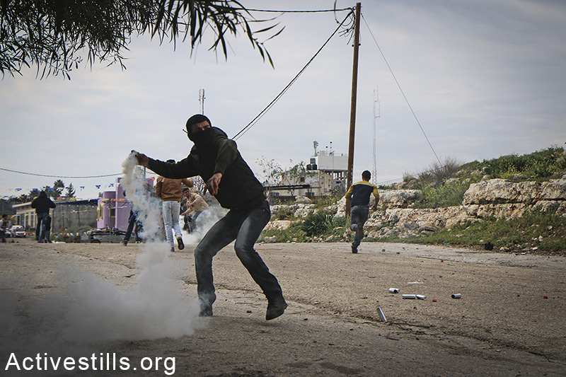 צעיר זורק חזרה גז מדמיע אל חיילים, במהלך הפגנה נגד סגירת השער המזרחי של הכפר, אזון, הגדה המערבית, 14 פברואר, 2015. אחמד אל-באז / אקטיבסטילס
