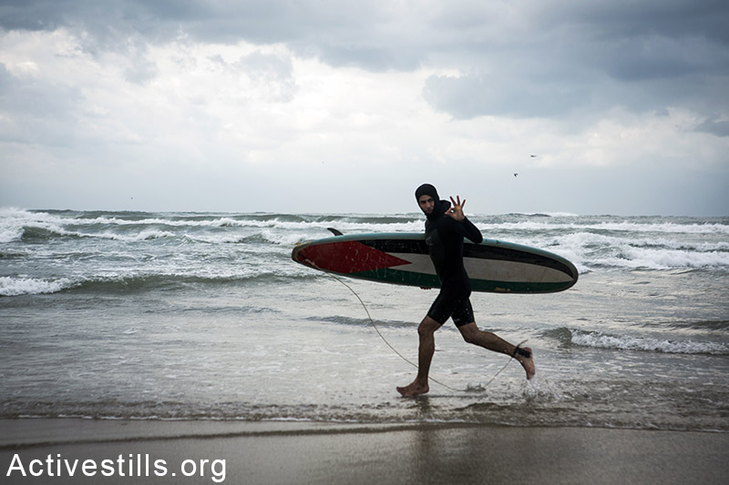צעיר עזתי בדרך לגלישה, החוף של עזה, 2 פברואר, 2015. אן פאק / אקטיבסטילס