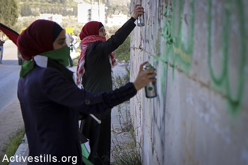 נערות פלסטיניות מרססות כתובות גרפיטי במהלך הפגנה נגד הכיבוש בכפר בורין, מטרים ספורים מהמקום בו הרג הצבא את אחמד אל נג'אר שבוע קודם לכן. 7 בפברואר, 2015.