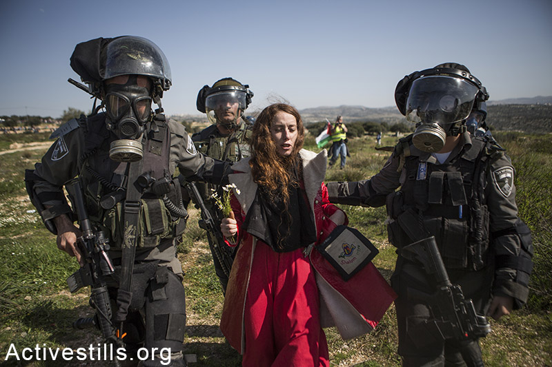 חיילי משמר הגבול עוצרים פעילה ישראלית במהלך הפגנה לציון עשר שנים למאבק נגד הגדר בכפר בילעין, 27 בפברואר, 2015.