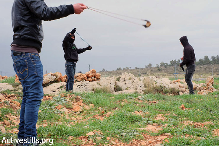 צעירים פלסטינים מיידים אבנים במהלך ההפגנה השבועית נגד הכיבוש בכפר נבי סלח, 13 בפברואר 2015.