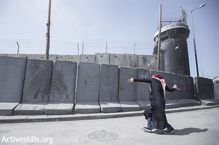 אישה פלסטינית מיידה אבנים בהפגנת יום האישה הבינ״ל סמוך למחסום קלנדיה, 7 במרץ, 2015. (אקטיבסטילס)