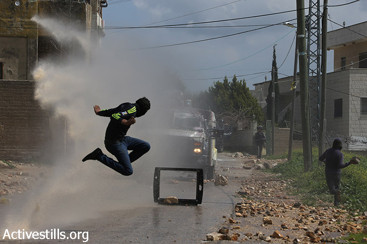 צעיר פלסטיני קופץ באויר בזמן שתותח מים צבאי יורה עליו מים, במהלך ההפגנה השבועית נגד הכיבוש בכפר קאדום, 13 במרץ, 2015. (אקטיבסטילס)