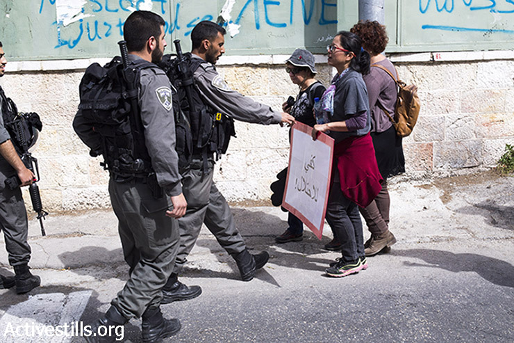 שוטר חוטף שלט ממפגינה בהפגנה נגד פינוי משפחות מבתיהן בירושלים המזרחית, 27 במרץ, 2015. (אקטיבסטילס)