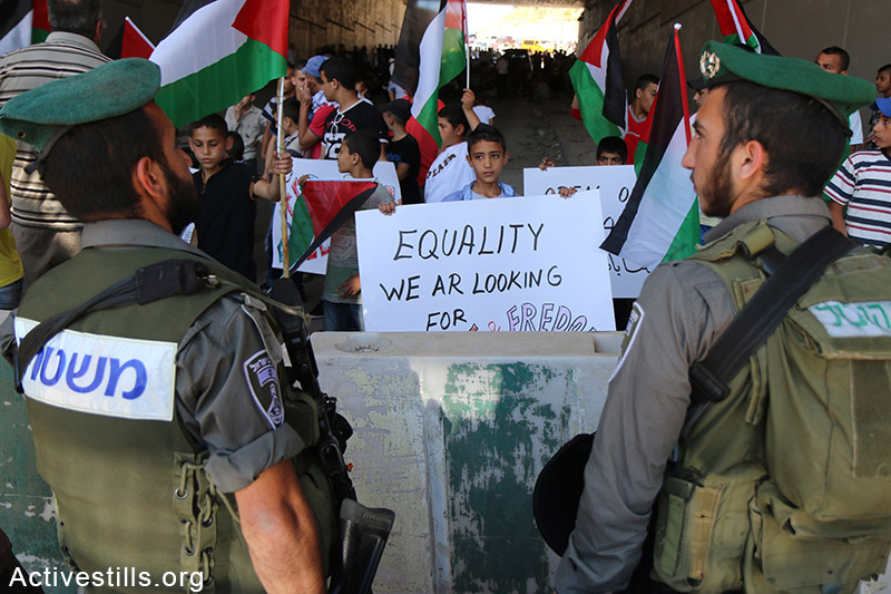 נערים נושאים שלטים במהלך הפגנה נגד הגבלות תנועה, כפר א-זעים, הגדה המערבית, 8 מאי, 2015. אחמד אל-באז / אקטיבסטילס