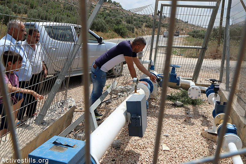 פלסטיני בודק את ברז המים הראשי בכפרו לאחר שחברת ׳מקורות׳ האיטה את אספקת המים ללא הסבר, הכפר קאוורת בני חוסאם, הגדה המערבית, 23 מאי, 2015. אחמד אל-באז / אקטיבסטילס