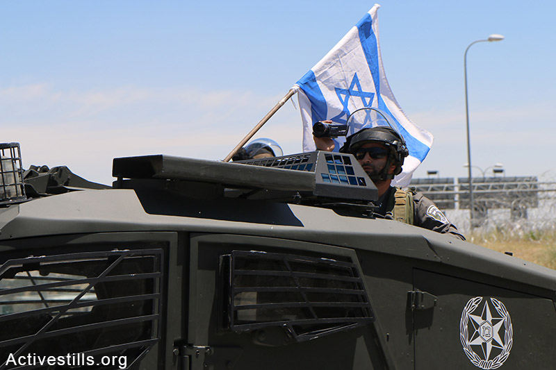חייל מצלם פני מפגינים במהלך מחאה נגד הגבלות תנועה, כפר א-זעים, הגדה המערבית, 8 מאי, 2015. אחמד אל-באז / אקטיבסטילס