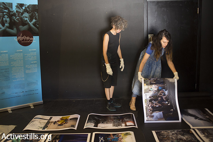 חברות קולקטיב אקטיבסטילס תולות את תערוכת הצילומים ״קיץ 2014״ המציגה תמונות מעזה במהלך המלחמה האחרונה, כחלק מפסטיבל סולידריות- אמנות ואקטיביזם שהתקיים בתאטרון יפו. 29 באפריל, 2014.