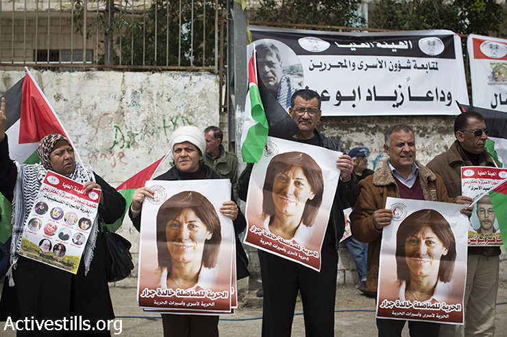 מפגינים פלסטינים מחזיקים תמונות של האסירה הפלסטינית חלידה ג'ראר, חברה במועצה המחוקקת הפלסטינית, במהלך הפגנה לציון יום האסיר הפלסטיני, מחוץ לכלא הצבאי עופר, סמוך לבייתוניא. 16 באפריל, 2015.