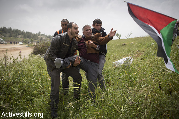 מפגינים נושאים גבר פלסטיני אשר נפצע במהלך הפגנה לציון יום האסיר הפלסטיני מול הכלא הצבאי עופר, סמוך לבייתוניא, 16 באפריל, 2015.